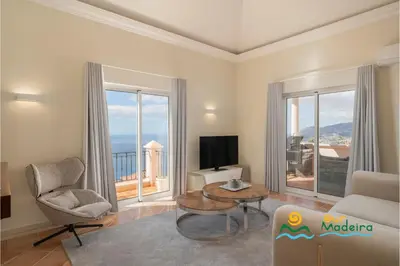 a living room with a couch chair and a tv and windows at OurMadeira - Palheiro Ocean in Funchal