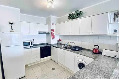 a white kitchen with white cabinets and a dishwasher at Mar Sereno Praia Formosa in Funchal