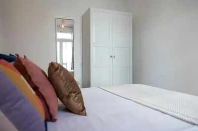 a bedroom with a white bed with colorful pillows at Apartamentos Progresso 1º Dto in Funchal