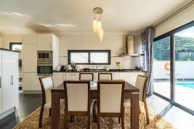 a kitchen with a dining room table and chairs at Villa Alex,pool and ocean view in Calheta