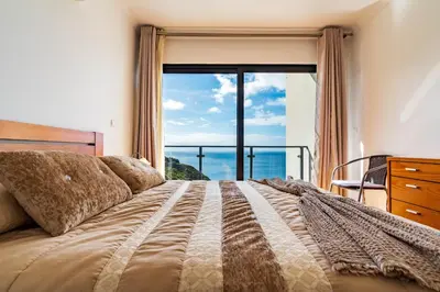 a bedroom with a bed with a large window at Villa Alex,pool and ocean view in Calheta