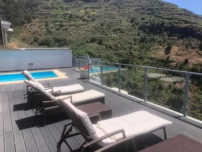 a deck with two lounge chairs and a swimming pool at Villa Alex,pool and ocean view in Calheta