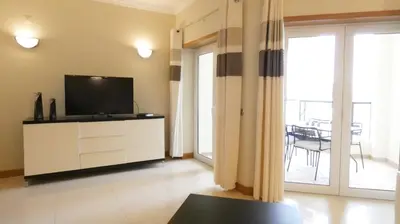 a living room with a flat screen tv on a cabinet at Apartamento Íris in Lagos