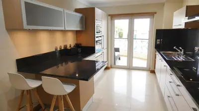 a kitchen with a black counter top and white cabinets at Apartamento Íris in Lagos