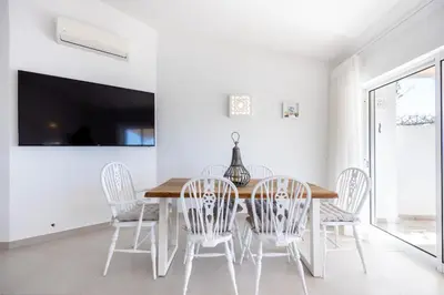 a dining room with a wooden table and white chairs at CoolHouses Algarve Luz, 3 Bed townhouse, lovely sea views, village centre, Casa Limoeiro 54LBC in Luz