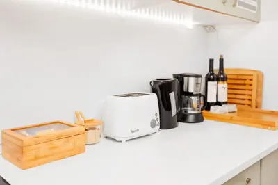 a kitchen counter with a toaster and bottles of wine at Quintinha Tropical - Panoramic Gateway to Madeira in Funchal