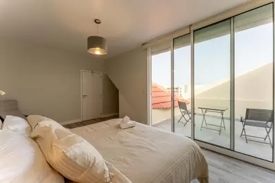 a bedroom with a bed and a balcony with a table at Penthouse Formosa Sunset and Beach in Funchal