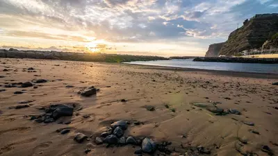 a beach with rocks on the sand and the water at Typical House -Madeira Inn Group in Calheta