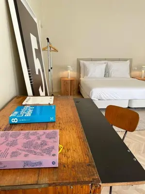 a room with a table with a bed and a desk with a book at Downtown collection apartments in Funchal