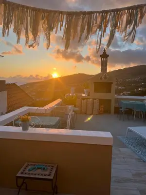 a view of a sunset from a patio with a table at CASA BOHO your happy place in Calheta in Calheta