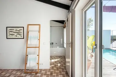 a bathroom with a glass door leading to a pool at Sanderling beach & dune house in Carrapateira