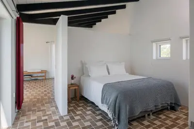 a bedroom with a white bed in a room at Sanderling beach & dune house in Carrapateira