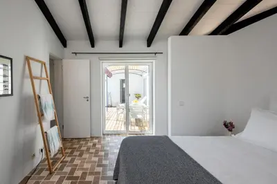 a bedroom with a bed and a door to a patio at Sanderling beach & dune house in Carrapateira