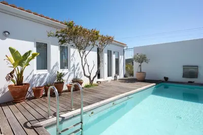 a house with a swimming pool and a wooden deck at Sanderling beach & dune house in Carrapateira