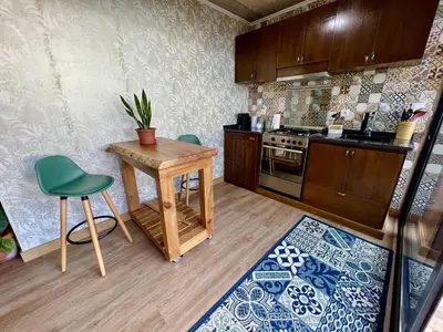 a kitchen with a wooden table and a green chair at Victoria Ocean View Room in Ponta do Pargo
