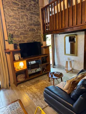 a living room with a couch and a television at Victoria Tiny Stone House in Ponta do Pargo