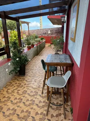 a table and chairs on a patio with plants at Victoria Tiny Stone House in Ponta do Pargo