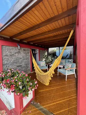 a porch with a hammock and chairs and flowers at Victoria Tiny Stone House in Ponta do Pargo