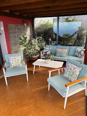 a patio with three chairs and a couch and a table at Victoria Tiny Stone House in Ponta do Pargo