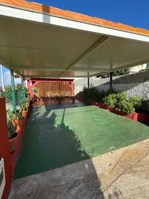 a patio with a green floor under a roof at Victoria Tiny Stone House in Ponta do Pargo