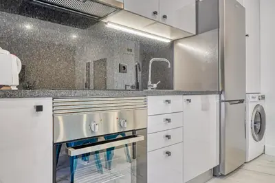 a kitchen with white cabinets and a stainless steel refrigerator at Beco Santa Emilia 2F, a Home in Madeira in Funchal