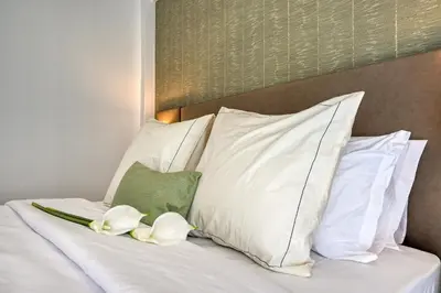 a bed with white pillows and flowers on it at Beco Santa Emilia 4Q, a Home in Madeira in Funchal