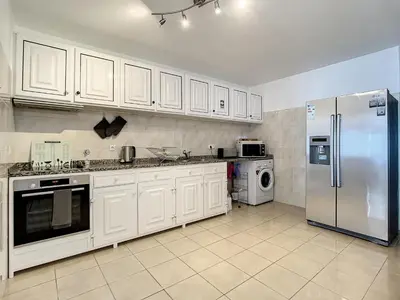 a kitchen with white cabinets and a stainless steel refrigerator at Villa Formosa View by Atlantic Holiday in Funchal
