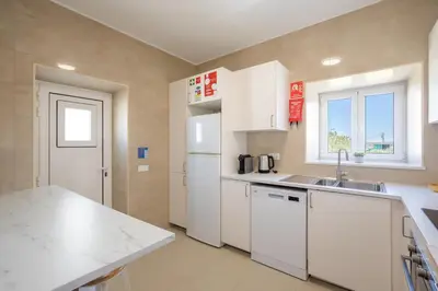 a kitchen with white cabinets and a counter top at Casa 7 Gerações in Sagres