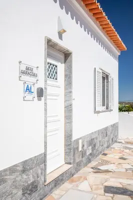 a white house with a white door and a sign at Casa 7 Gerações in Sagres