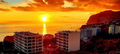 a sunset over a city with a building and the ocean at Horizon Dream in Funchal