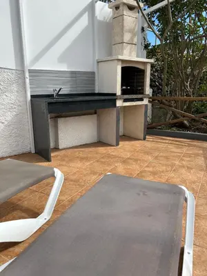 a patio with a table and an outdoor oven at Tropical Garden in Arco da Calheta
