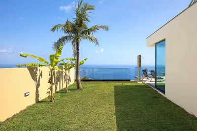 a view of the ocean from the backyard of a house at Villa Ohana in Estreito da Calheta