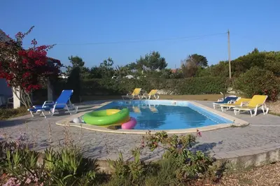 a swimming pool with a bunch of chairs around it at Villa Mourisca in Aljezur