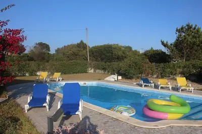 a swimming pool with blue and yellow chairs and a pool noodle at Villa Mourisca in Aljezur
