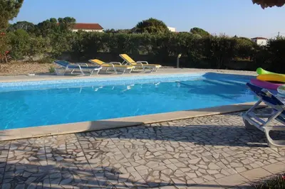 a swimming pool with chairs and a table at Villa Mourisca in Aljezur
