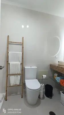a bathroom with a toilet and a shelf with towels at Suite Palms in Funchal