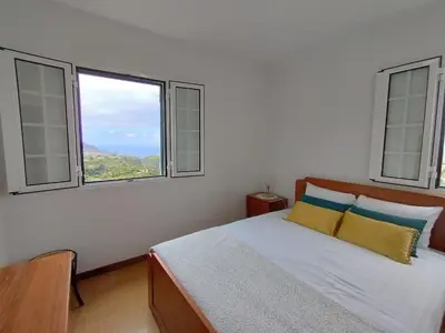 a bedroom with a large bed with two windows at Terra Batista house in Porto da Cruz