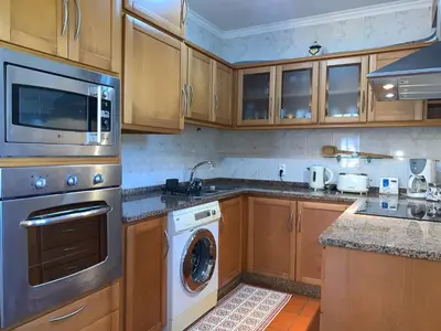 a kitchen with wooden cabinets and a washer and dryer at Terra Batista house in Porto da Cruz