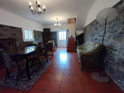 a living room with a table and chairs and a stone wall at Terra Batista house in Porto da Cruz