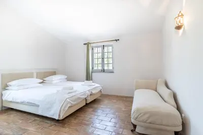 a white bedroom with a bed and a chair at Casa Sapo Gordo in Luz