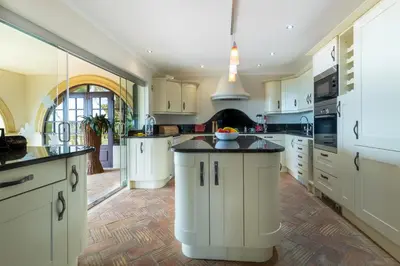 a large kitchen with white cabinets and black counter tops at Casa Sapo Gordo in Luz