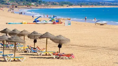 a beach with people laying in chairs and umbrellas at Lagos Ocean Breeze 1 by Homing in Lagos