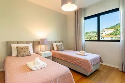 a bedroom with two beds and a large window at Leonor Seaview Apartment in Funchal