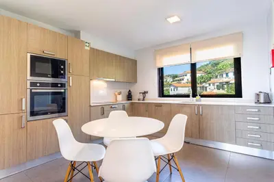 a kitchen with a white table and white chairs at Leonor Seaview Apartment in Funchal