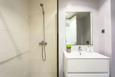 a white bathroom with a shower and a sink at Leonor Seaview Apartment in Funchal
