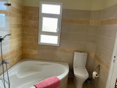 a bathroom with a tub and a toilet and a window at Belle Vue in São Jorge