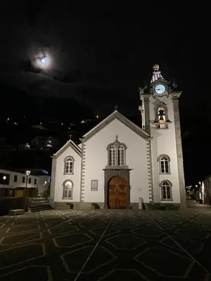 a white church with a clock tower at night at 2 bed room apartment , sea view, 10 minutes walk to the beach in Ribeira Brava