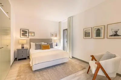 a white bedroom with a bed and a chair at Fort Bay Suite Apartments in Machico