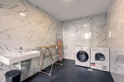 a bathroom with a sink and a washing machine at Fort Bay Suite Apartments in Machico