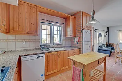 a kitchen with wooden cabinets and a wooden table at Casa Lady D'Avila in Aljezur